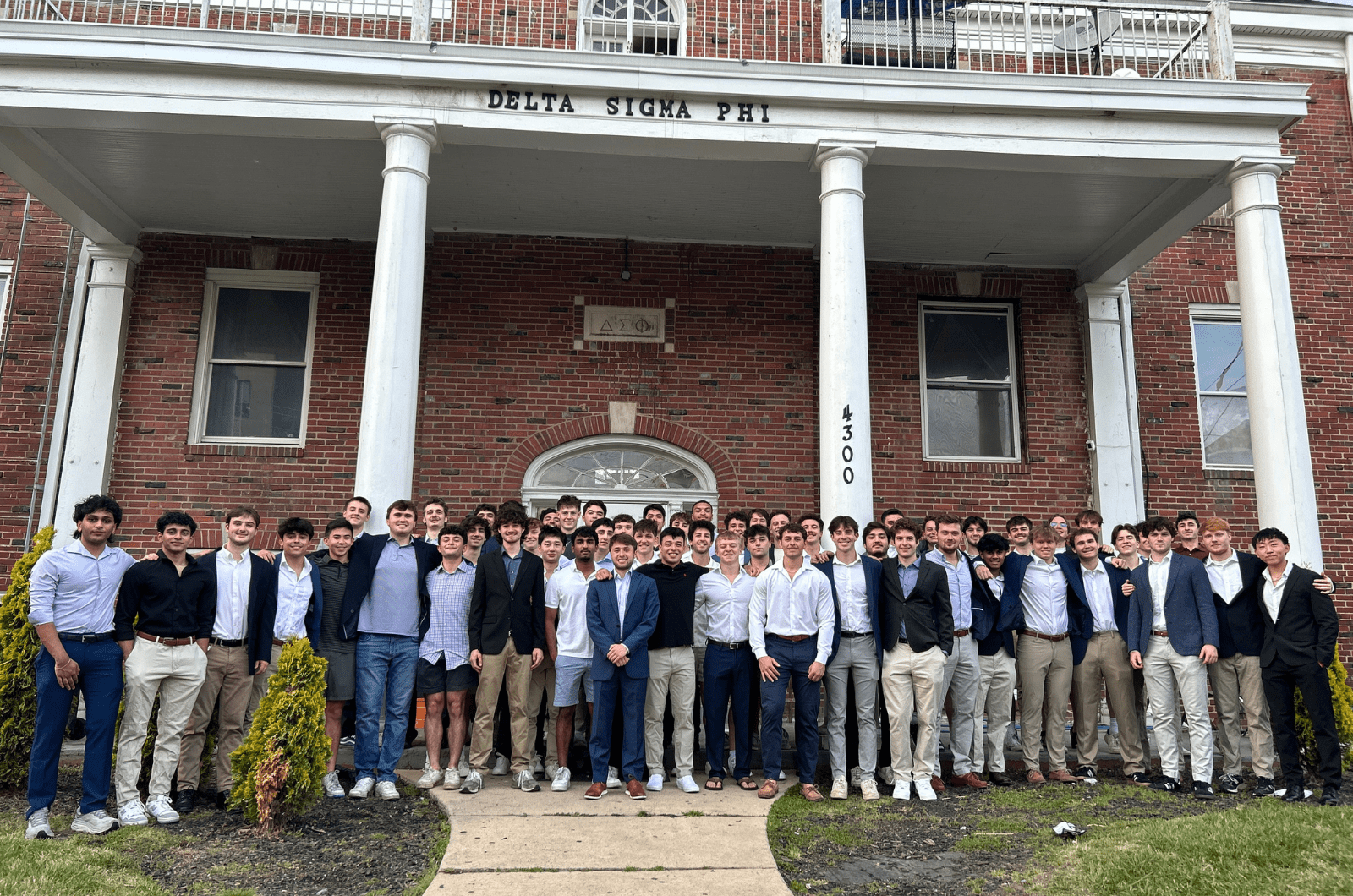 Members of Delta Sigma Phi in front of their chapter house